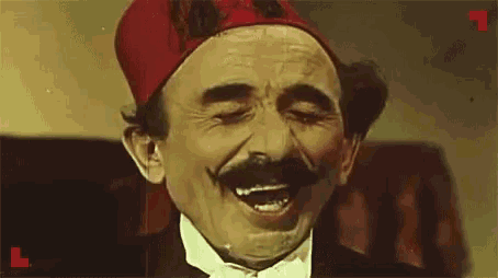 a man with a mustache and a red hat is making a funny face .