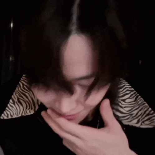 a blurry picture of a person covering their mouth with their hand and the word wow written on it .
