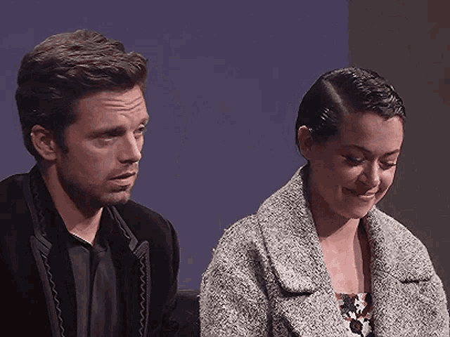 a man and a woman are sitting next to each other and smiling .