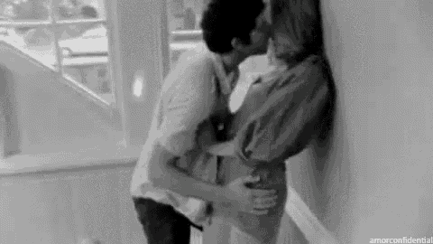 a black and white photo of a man kissing a woman on the cheek .