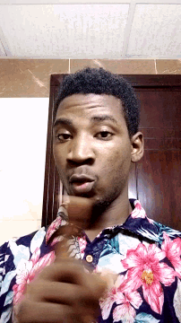 a young man wearing a floral shirt is pointing at the camera