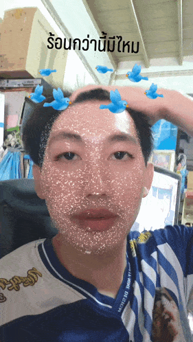 a man wearing a blue and white striped shirt has blue birds on his face and a caption in thai