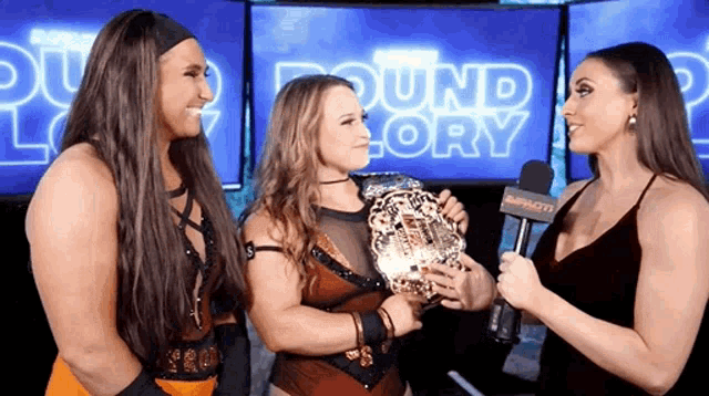 a woman is holding a trophy in front of a sign that says round glory
