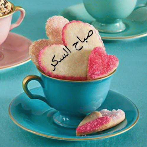 a cup of coffee with a heart shaped cookie that says " صباح السكر " on it