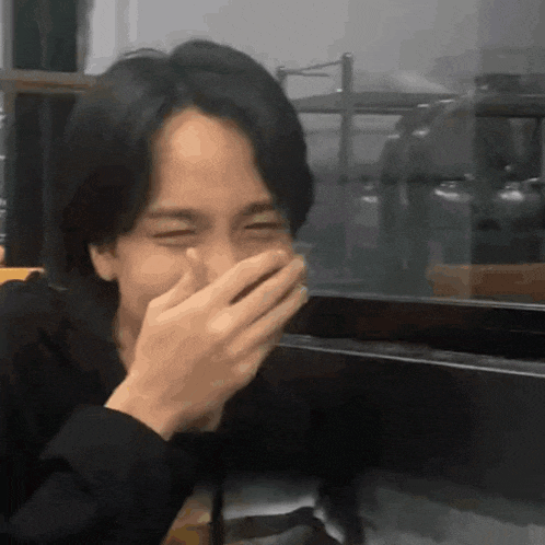 a man covering his mouth with his hands laughing