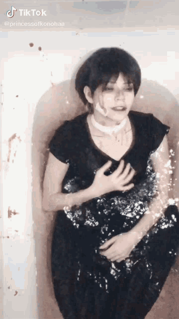 a woman in a black dress is in a bathtub with blood coming out of her mouth