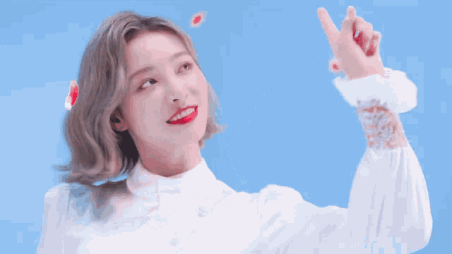 a woman in a white dress is pointing at something in the sky