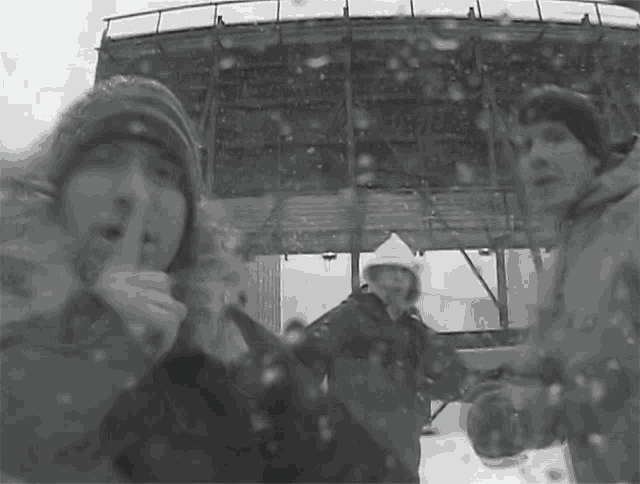 a group of people standing in the snow with one covering his mouth