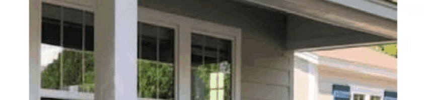 a house with a porch and a lot of windows and a reflection of trees in the windows .