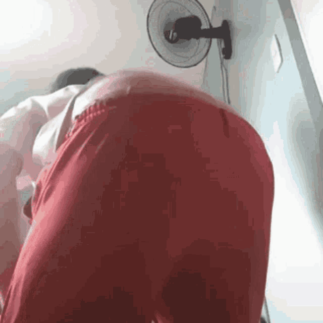 a man in red shorts is standing in front of a fan .