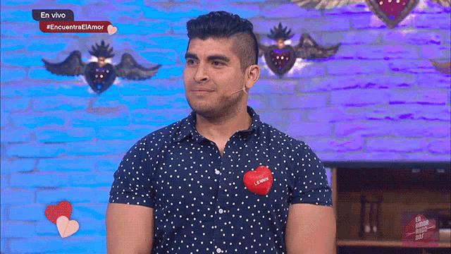 a man in a polka dot shirt has a red heart on his chest that says " i love you "