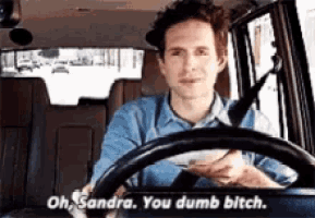 a man driving a car with the words oh sandra you dumb bitch on the steering wheel