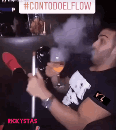 a man is smoking a hookah and drinking from a glass