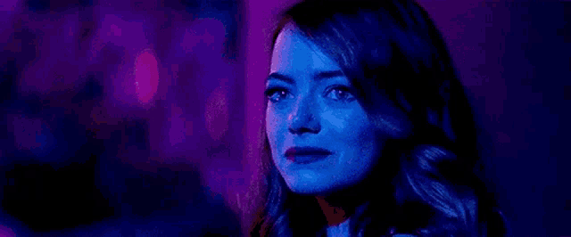 a close up of a woman 's face in a dark room with blue lights .