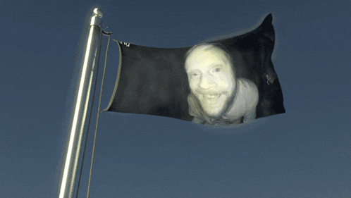 a black flag with a picture of a man on it is flying in the wind