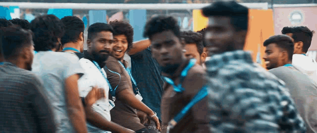 a group of young men are standing in a crowd with one wearing a lanyard