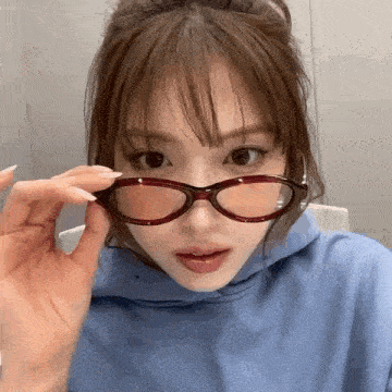 a close up of a woman wearing glasses and a blue sweatshirt .