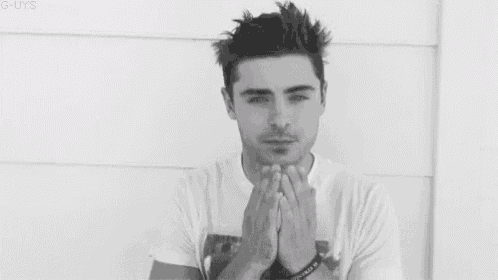 a black and white photo of a young man with his eyes closed and his hands on his face .