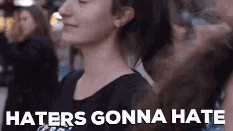 a woman is standing in front of a crowd of people with the words `` haters gonna hate '' written on the bottom .