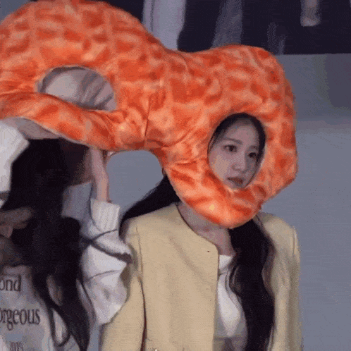 a woman wearing a giraffe hat is holding a stuffed animal on her head .