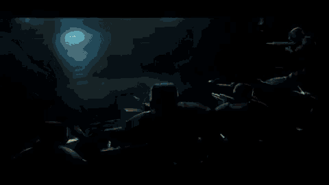a group of people are standing in a dark room with a glowing light coming out of their mouths .