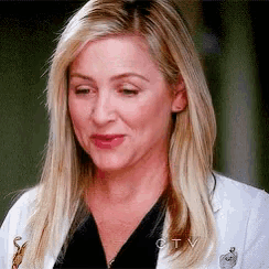 a close up of a woman wearing a white coat and black shirt .