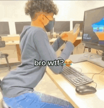 a man wearing a mask is sitting at a desk looking at his phone with the words bro wtf below him