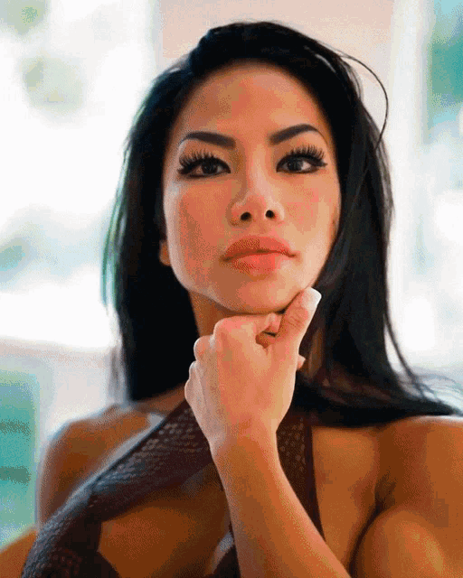 a woman with a hand on her chin looks at the camera