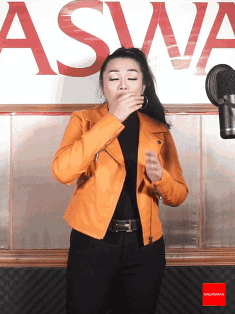 a woman covering her mouth in front of a sign that says aswa on it