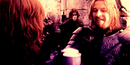 a man in a knight 's armor is talking to a woman while holding a cup of coffee .