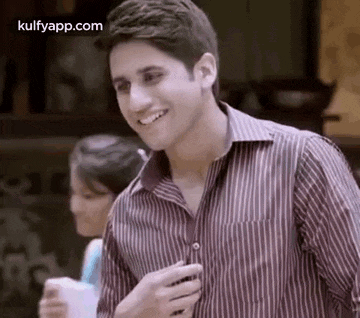 a man in a striped shirt is smiling while standing next to a woman in a restaurant .