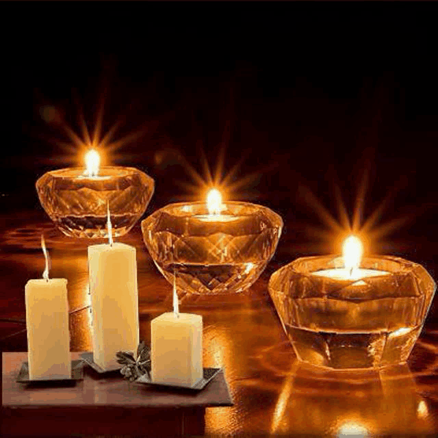a group of lit candles in glass holders on a wooden table .