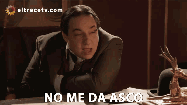 a man in a suit and tie is sitting at a table with the words me divierte mucho below him
