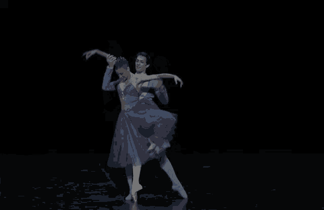a man is holding a woman in his arms while they dance