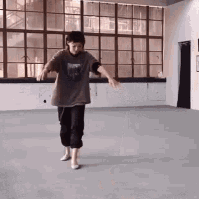 a young man is dancing in a room with lots of windows .