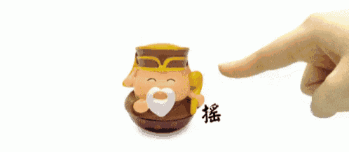 a hand is touching a cartoon figurine with chinese writing on it .