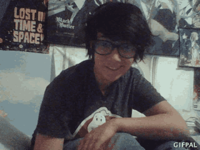a boy wearing glasses sits in front of a poster that says lost in time and space