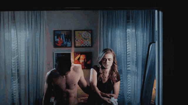 a man without a shirt is standing next to a woman