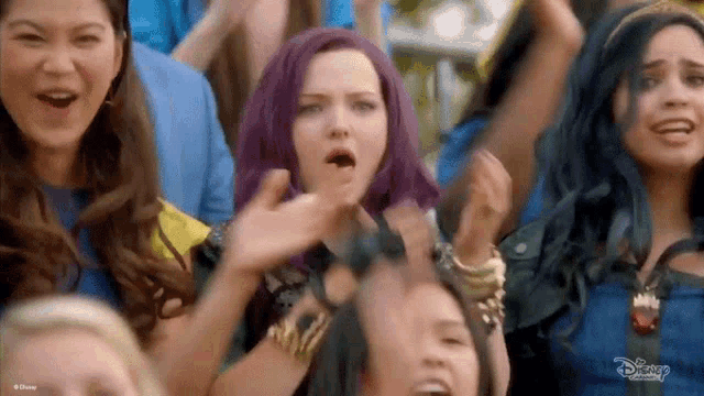 a group of young women are standing in a crowd and cheering .