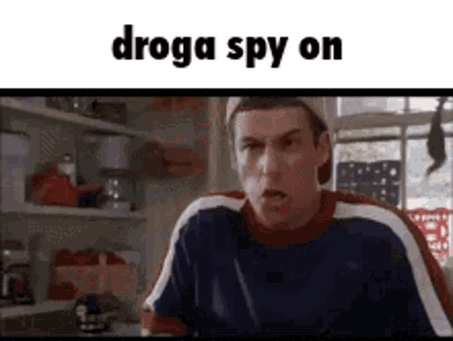 a man is sitting in a kitchen with the words `` droga spy on '' written on the screen .
