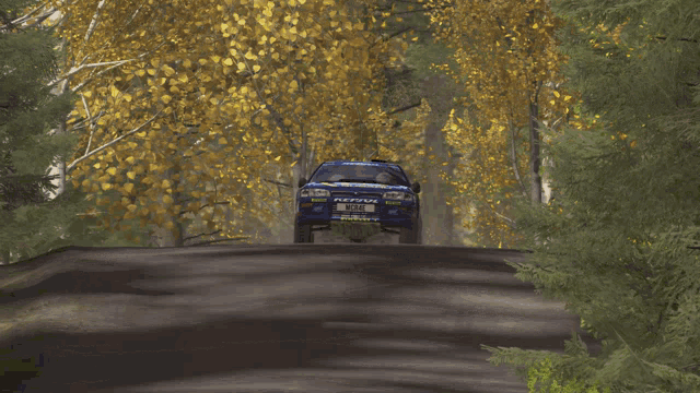a subaru car is driving down a road in the woods