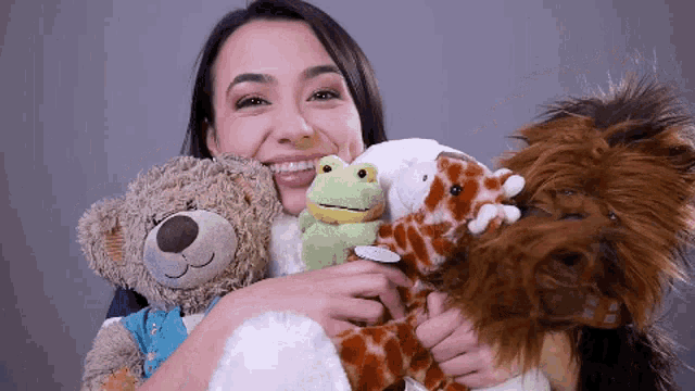 a woman is holding stuffed animals including a teddy bear and a frog