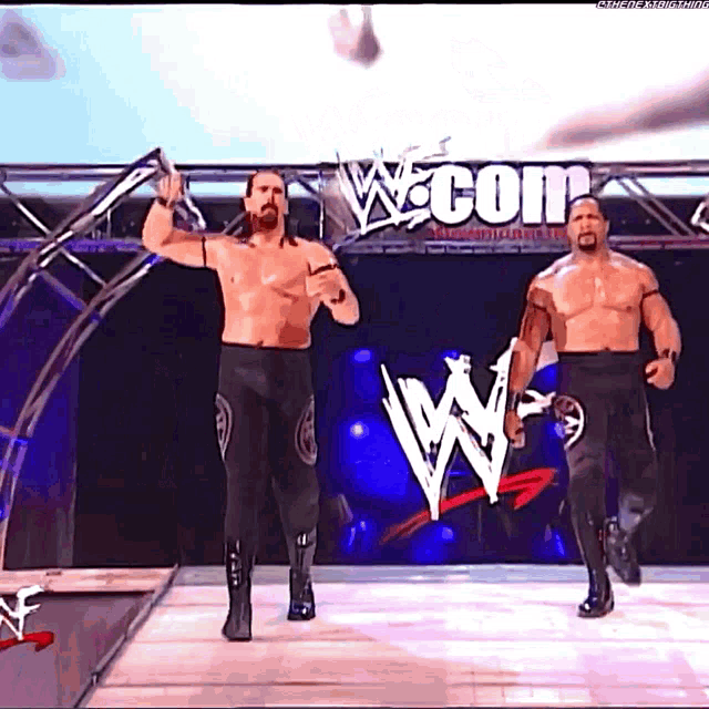 two wrestlers are walking down a ramp in front of a wwe logo