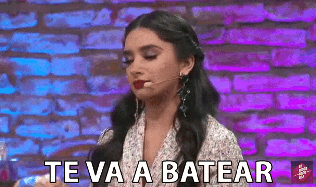 a woman is standing in front of a brick wall and says te va a batear