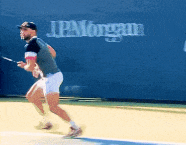 a man is playing tennis in front of a jp morgan sign