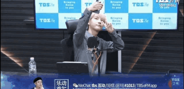a man is taking a selfie in front of a tbs fm banner