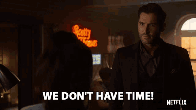 a man in a suit says " we don 't have time " in front of a scotty 's tavern sign