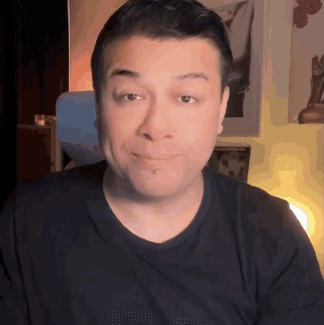 a man with a piercing in his nose is smiling for the camera
