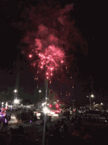 a fireworks display is being watched by people in a parking lot