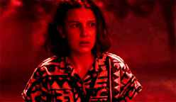 a woman is standing in front of a red background and looking at the camera .